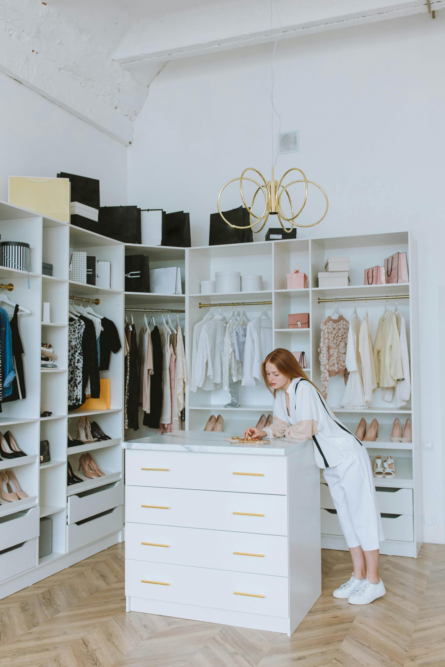 Elegant wardrobe with a red-haired woman organizing clothes in a modern fashion boutique.